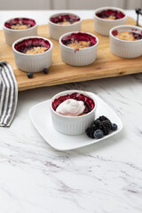 Wall Mural - White Ramekins of Blueberry and Blackberry Cobbler on a Wooden Tray; One Isolated in Front; Kitchen Countertop