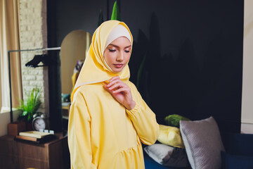 Portrait of positive pretty young Arabian woman in pink headscarf touching face with hand.