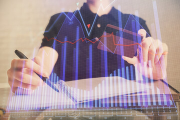 Double exposure of man hands holding a credit card and Forex graph drawing. Stock trading and digital fintech in Internet E-commerce concept.