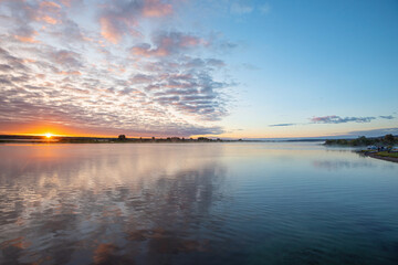 Wall Mural - sunrise, sunset over the river crept a small fog over the water, beautiful colorful clouds.