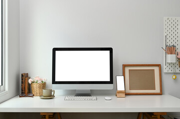 Fototapete - Workspace with white screen desktop computer, smart phone and stuff on white table.