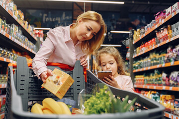 family at the supermarket. woman in a pink shirt. people choose products. mother with daughter.