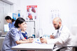 © DC Studio - Doctor explaining treatment to mother of sick child in hospital office holding pills bottle. Healthcare physician specialist in medicine providing health care services treatment examination.