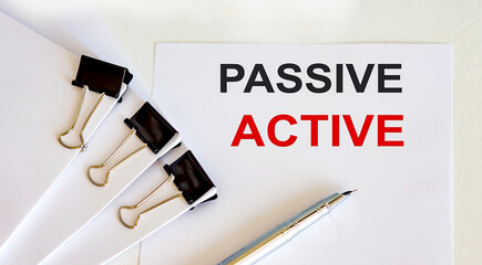 Poster - PASSIVE ACTIVE written on a white page with office tools