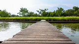 Fototapeta Natura - Old brown wooden bridge with trees and sky as background.