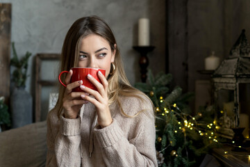 Pretty woman drinking hot winter drink from red cup