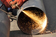Welder worker welding a wide metal pipe tube with a oxy-fuel cutting torch, with flame and sparks