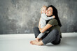 © muse studio - a young kind mother and her little daughter baby kids, hugging show a warm attitude to each other. Background gray design wall in the photo Studio.