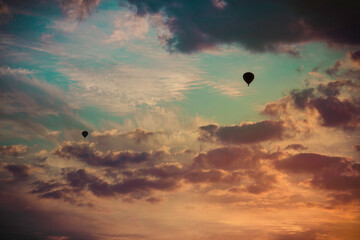 Two Hot Air Balloons fly towards the sunset.