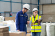 © NVB Stocker - Female Inventory Manager checking stock on Digital Tablet. Man warehouse worker with hard hat safety helmet at storage buildings