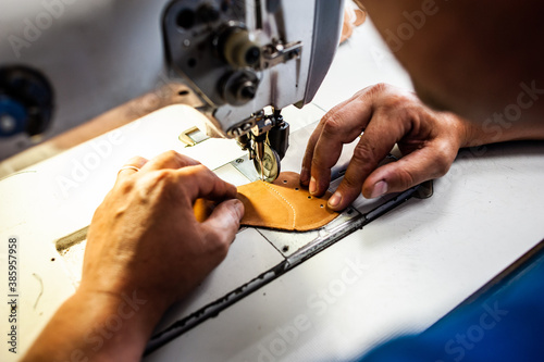 The master sews leather garments at the factory