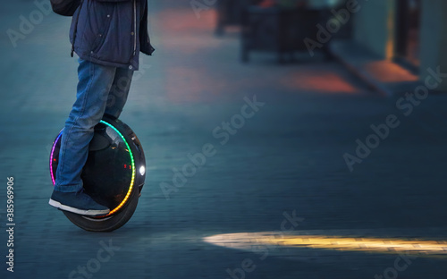 Riding fast on electric unicycle on city street at night with diode headlights. Night riding, man on electric mono-wheel riding fast (EUC). Mobile portable individual transportation vehicle.