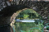Fototapeta Do pokoju - The river of the Garden of Ninfa, medieval stone bridge over the lake, relaxing view, Italy