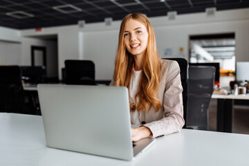 Business young woman sitting at table with laptop in office