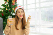 © chinnarach - close up young asian woman listening music while holding wineglass and dancing at living room for celebration merry Christmas season festival concept