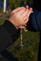 Wall Mural - Mother and little son hold each other's hand with a rosary.