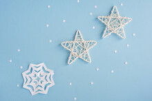 White Stars Made Of Rattan And A Snowflake Made Of Paper On A Blue Speckled Background