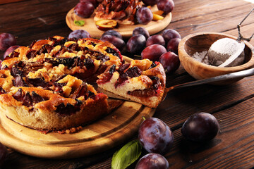 Wall Mural - Rustic plum cake on wooden background with plums around.