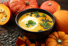 Roasted Pumpkin And Carrot Soup With Cream And Pumpkin Seeds On Wooden Background.