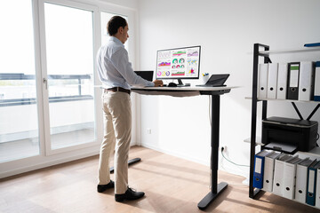 man working on computer at standing desk