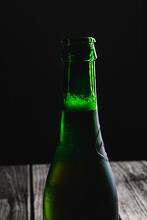 Green Beer Bottle Full And Opened With Blond Beer Backlit On A Black Background