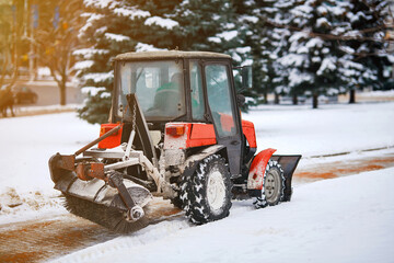 Wall Mural - Snow removal tractor cleans alley in park. Tractor removing snow, sprinkle salt and sand to prevent slipping. Municipal service cleaning sidewalk from snow with snow plow and rotating brush