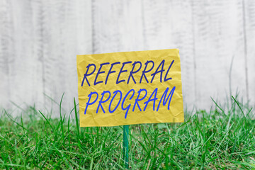 Poster - Word writing text Referral Program. Business photo showcasing employees are rewarded for introducing suitable recruits Plain empty paper attached to a stick and placed in the green grassy land