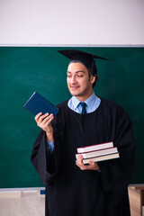 Young male graduate in front of board