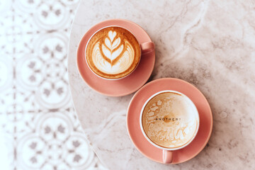 Wall Mural - Pink cup of cappuccino on marble table background. Love latte art on the top of it.