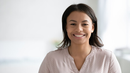 Narrow wide panoramic view headshot portrait of smiling African American young woman pose at home. Banner profile picture of happy biracial female renter or tenant look at camera. Copy space.