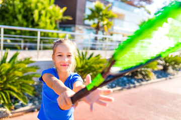 little girk playing tennis in tropical place outdoors