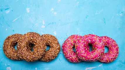 Glazed doughnuts with pink and chocolate icing with sprinkles on a blue background,space for text,