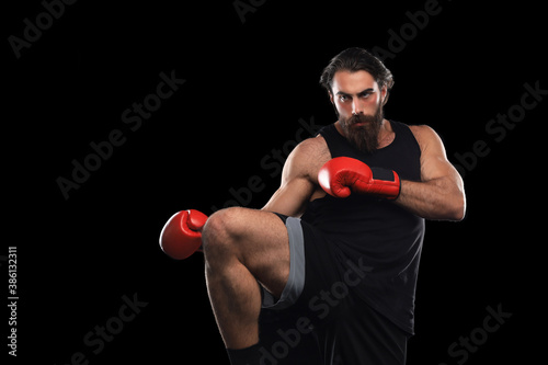 Fotomural Kickboxer man fighting against black background. Sport concept.