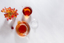 Sunny Autumn Teatime With Rose Hip Tea With Teapot, Cup, Orange Rose Hip Branch With Shadows On White Wood Table Top View, Copy Space.