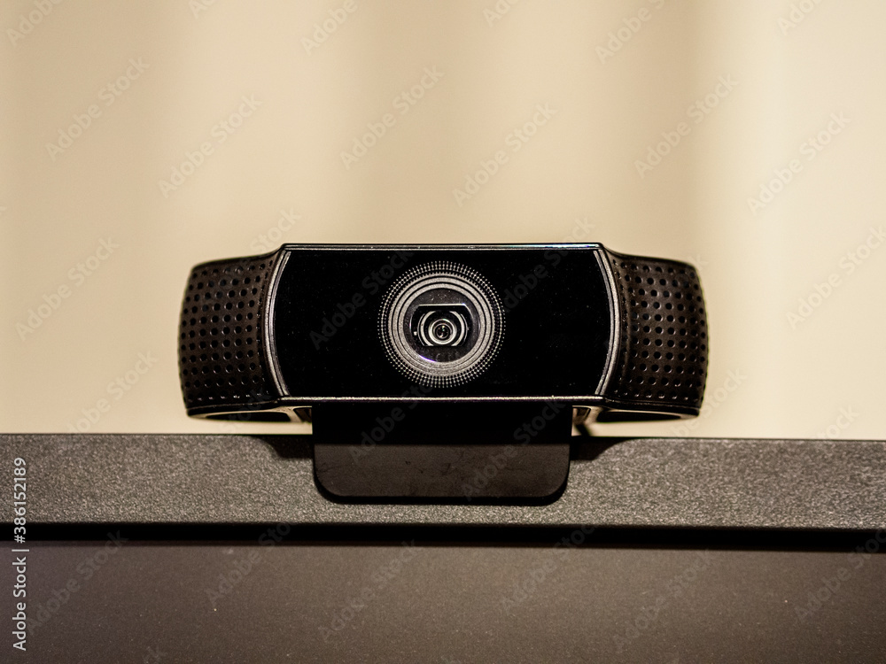 A black generic web camera on top of a screen. With a beige background ...