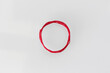 a red silk thread looped in a circle form on a soft white background with copy space