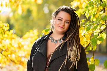 Wall Mural - Young happy woman with dreadlocks outdoors in autumn