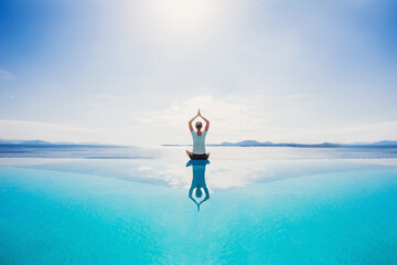 Young woman practicing yoga by the sea. Harmony, meditation, healthy lifestyle and travel concept. 