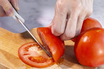 Woman's hands cutting fresh tomato slices