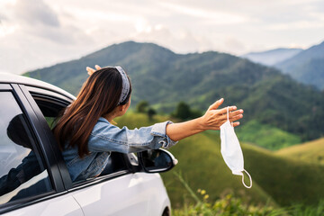 Wall Mural - Young woman traveler taking off surgucal mask and looking beautiful mountain view while travel driving road trip on vacation