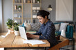 © fizkes - Serious young focused 30s indian business woman student freelancer sit at desk in modern cozy home office living room texting on laptop, do telecommute work remotely, solving issues distantly concept