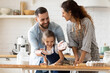 © fizkes - Happy parents with adorable little daughter having fun with dough, baking pastry or pie together, laughing father clapping hands with flour, overjoyed family enjoying leisure time in kitchen