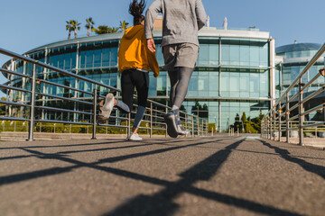 Back view of two fit runners jogging down the street in the morning