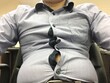 Man with big and fat belly wearing too small and tight shirt sitting on the chair. Need exercise for body fit. Healthcare and diet concept