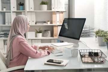 Poster - Contemporary serious Muslim businesswoman working with online data in office