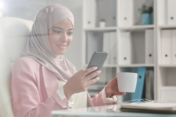 Poster - Happy restful Muslim businesswoman in hijab scrolling in smartphone at break