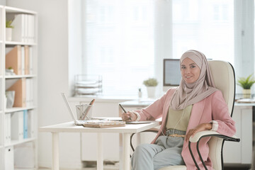 Poster - Young Muslim female in hijab and earphones retouching images or drawing sketch