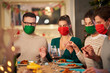 Group of friends in masks praying over Christmas Thanksgiving table at home