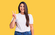 © Krakenimages.com - Young beautiful brunette woman wearing casual t-shirt smiling with happy face winking at the camera doing victory sign. number two.
