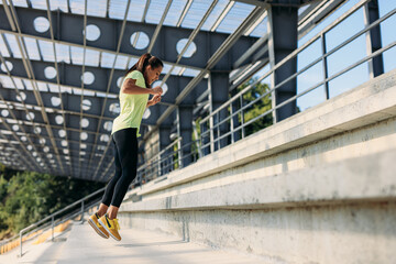 Wall Mural - Active woman in sportswear practising in jumping on stairs